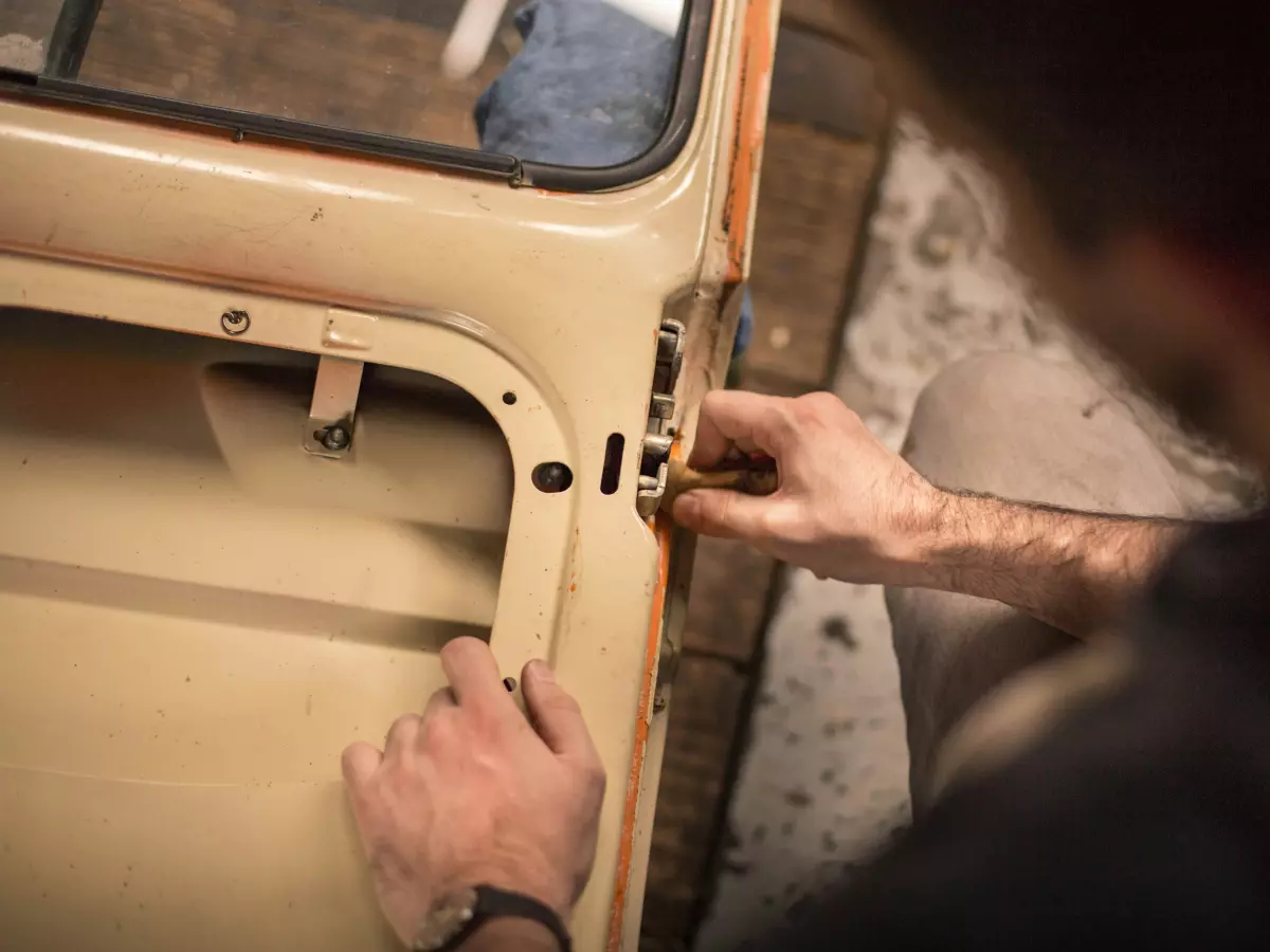 A man working on a car door, focusing on the door handle